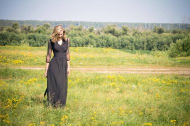 Siyah elbise giymiş bir kızın etrafında alanı yürüyor