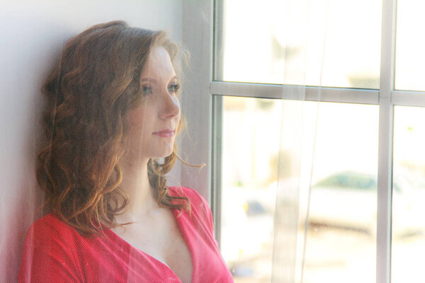 Беременная женщина в красном платье в светлой комнате
