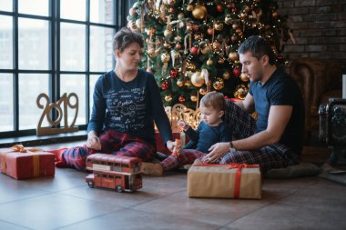 Aile yeni yılı. Küçük oğlu olan bir aile Noel ağacının altında oturuyor.. 