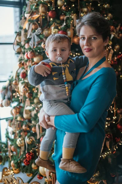 Family New Year. Portrait of mom with baby at the New Year tree