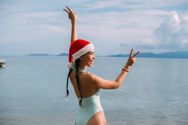 Girl in a swimsuit and New Year's hat on the ocean on a tropical island. — Stock Photo, Image