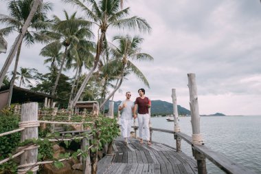 Okyanusta Noel şapkası takmış genç eşcinsel çift.