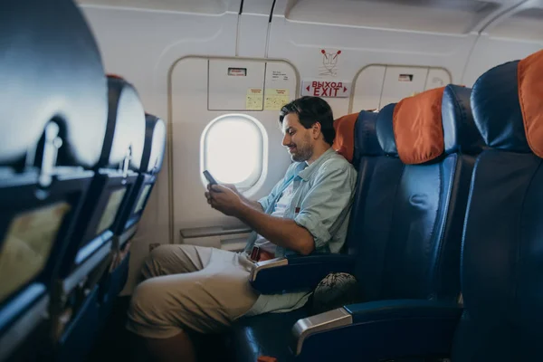 Парень летит в самолете с телефоном в руке . — стоковое фото