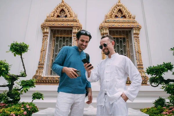 Men in a Buddhist temple read tourist information, look at a map