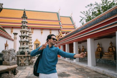 Budist tapınağındaki bir adam fotoğraf çeker, telefonda selfie çeker..