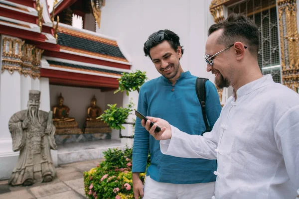 Men in a Buddhist temple read tourist information, look at a map