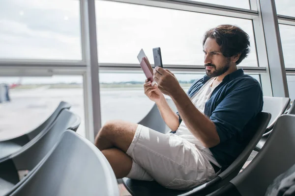 A man sits near the gate at the airport with a telephone. — Stock Photo, Image