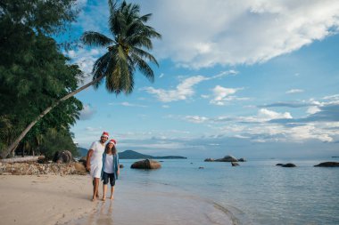 Genç bir çift yeni yıl şapkasıyla sevinçle denizde koşuyor..