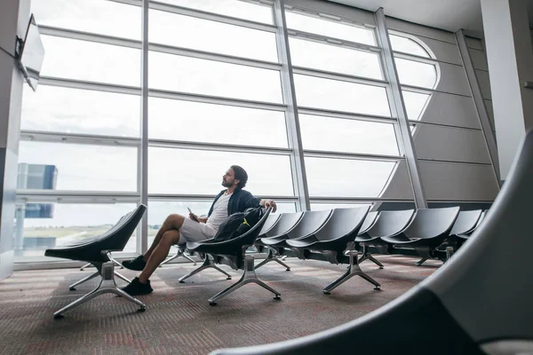 Мужчина сидит в комнате ожидания у ворот аэропорта . — стоковое фото