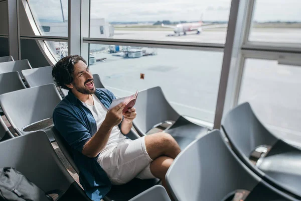 A man sits in a waiting room at the gate at the airport.