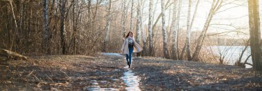 Bir kız son karda bir orman izi boyunca yürür.