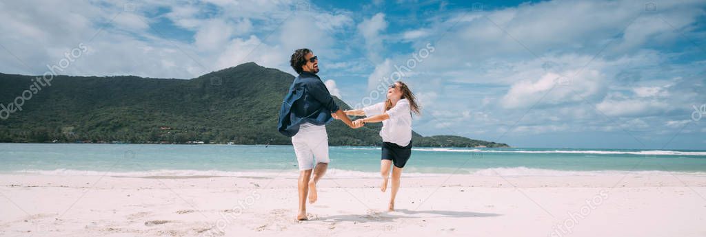 A pair of lovers have fun running around on a tropical beach.