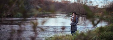 Bulutlu bir akşamda köprünün kıyısında bir kız duruyor.