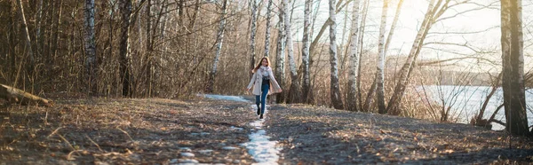 Een meisje loopt langs een bos parcours door de laatste sneeuw. — Stockfoto