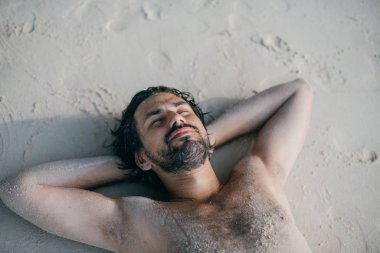 Yakışıklı bir adam okyanusun kıyısında kumların üzerinde yatıyor.. 