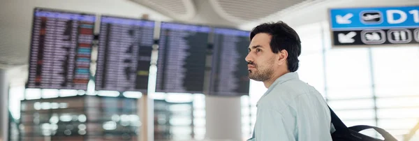 The guy at the airport waiting for departure, looking schedule. — Stock Photo, Image