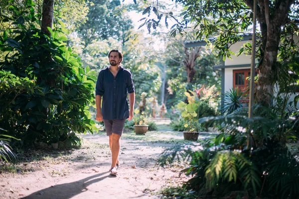 Um jovem caminha em um jardim tropical . — Fotografia de Stock