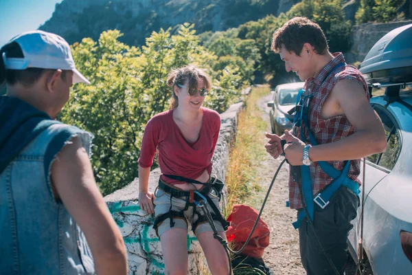 First climbing lesson with a trainer.  The girl puts on equipment and listens to the coach before climbing a rock in the mountains