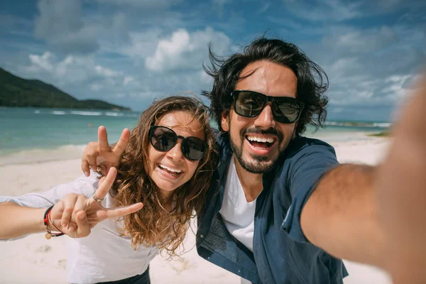 Een paar geliefden nemen een selfie op een tropisch strand. — Stockfoto