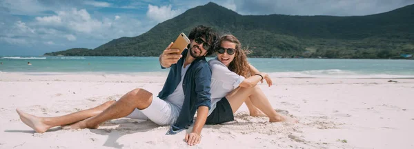 Para kochanków robi sobie selfie na tropikalnej plaży. — Zdjęcie stockowe
