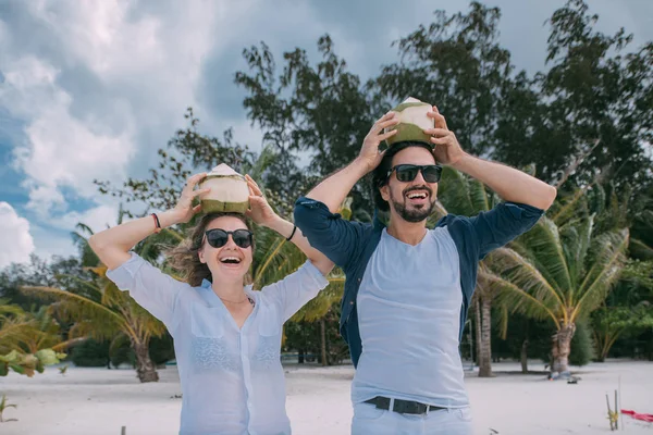 Gelukkige paren met cocktails op een tropisch strand. — Stockfoto