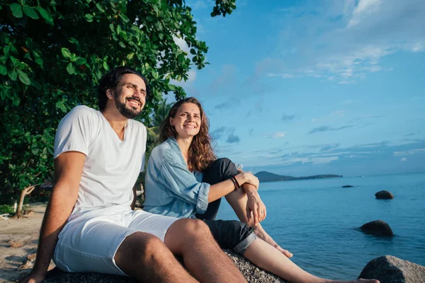 Een jongen en een meisje zitten op een steen aan zee.. — Stockfoto