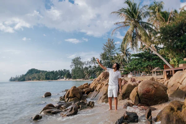 Egy férfi a trópusi parton, kövekben a tenger mellett.. — Stock Fotó