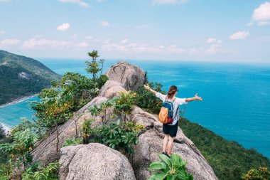 Bir kız destansı bir bakış açısıyla bir kayanın üzerinde duruyor. 