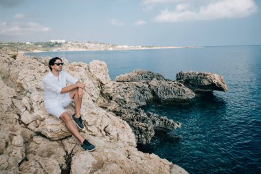 A man on the rocks overlooking the sea
