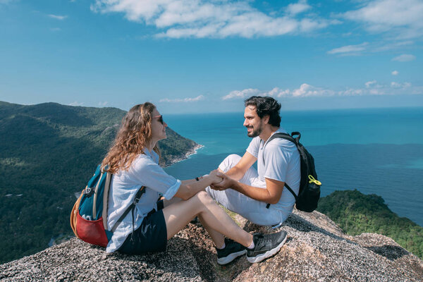 A couple stand on a rock at a viewpoint with an epic view of the