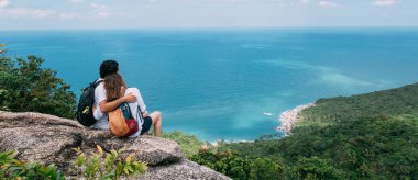 Bir çift, bir kayanın üzerinde destansı bir bakış açısıyla duruyor.
