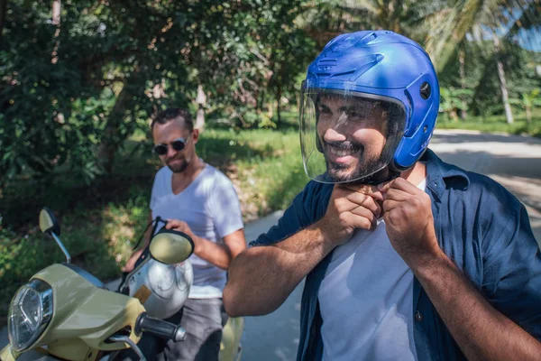 Dos hombres en motocicletas con cascos en palmeras en un tropical — Foto de Stock
