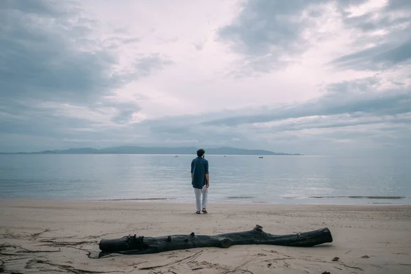Un hombre solitario camina por la playa en un día nublado —  Fotos de Stock
