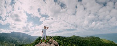 Destansı bir bakışla bir kayanın üzerinde duran bir adam. Popüler bir turizm merkezi. Tropik bölgelerde tatilde olan bir adam. Asya Maceraları.