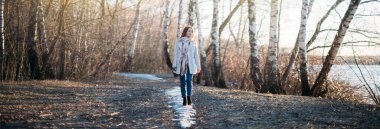 Bir kız son karda bir orman izi boyunca yürür. Hafif bir yağmurluk içinde genç bir kadın mutlu yürüyüşler, gün batımında ağaçlar arasında yol boyunca atlama