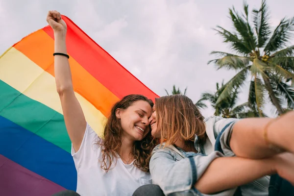 Dwie Kobiety Tęczową Flagą Plaży Tle Palm Para Młodych Lesbijek — Zdjęcie stockowe