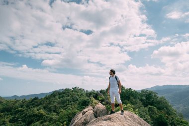 Destansı bir bakışla bir kayanın üzerinde duran bir adam. Popüler bir turizm merkezi. Tropik bölgelerde tatilde olan bir adam. Asya Maceraları.