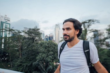 Bir adam gökdelenlerin arka planına karşı manzaraya hayran. Genç bir adam metropolde seyahat ediyor. Bir turist, büyük bir şehir ve parkın arka planına karşı bir bakış açısında duruyor.