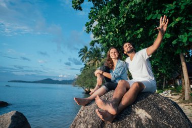 Bir adam ve bir kız deniz kenarında bir taşın üzerinde oturuyorlar. Aşıklar tropikal bir adada gökyüzüne hayran kalırlar. Sevgi dolu bir çift Avrupalı güneşe bakar ve tropik yeşillik ve gökyüzüne karşı gülümserler..