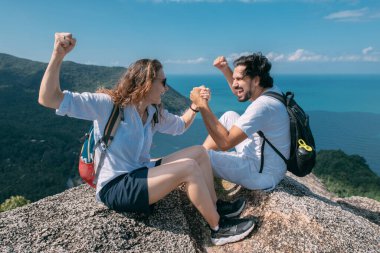 Bir adam ve bir kadın okyanus manzaralı bir kayanın üzerinde oturuyorlar. Popüler bir turizm merkezi. Tropik bölgelerde tatilde olan arkadaşlar..