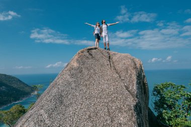 Okyanusun destansı manzarasına sahip bir çift kayanın üzerinde duruyor. Popüler bir turizm merkezi. Sevgililer tropik bölgelerde tatildeler. Tropiklerde balayı.