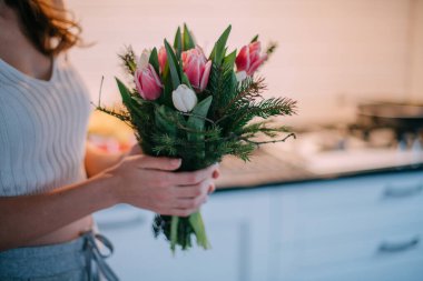 Bir kadının ellerinde bir buket çiçek. Uluslararası Kadınlar Günü. Genç bir kız lalelerin elinde topallıyor..