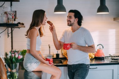 Sabahları evdeki mutfakta birbirini seven genç bir çift. Erkek ve kadın şık bir mutfakta eğlenceli bir kahvaltı yapıyorlar..