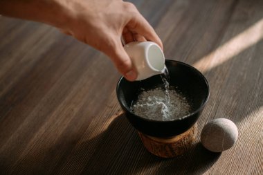 Yüz ve vücut bakımı. Ahşap bir masanın üzerindeki bir kasede kozmetik maske hazırlamak. Erkeklerin elleri pudra ve sudan maske yapar..