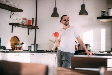 Yüzünde yamalar olan bir adam dinleniyor. Erkeklerin kişisel bakımı. Genç yakışıklı adam yüzüne bakar, mutfakta çay içer..