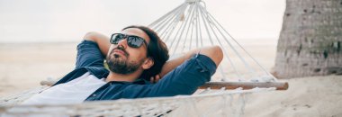 Bir adam sükunetten hoşlanır, okyanusun arka planında bir hamakta yatar ve günbatımını seyreder. Yakışıklı adam tropik bir adanın sahilinde gün batımıyla karşılaşır..