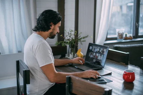 Workplace at home. A man works at a laptop at home, sits at a table in the living room during the day. Work from home.