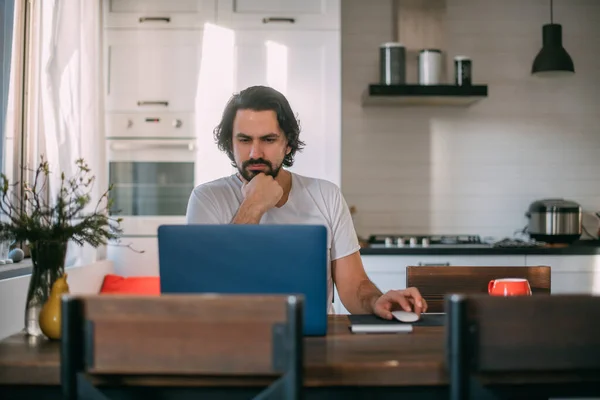 在家工作 一个男人在家里的笔记本电脑前工作 白天坐在客厅的桌子前 在家工作 — 图库照片