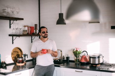 Yüzünde yamalar olan bir adam dinleniyor. Erkeklerin kişisel bakımı. Genç yakışıklı adam yüzüne bakar, mutfakta çay içer..