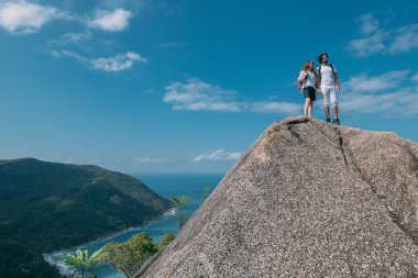 Okyanusun destansı manzarasına sahip bir çift kayanın üzerinde duruyor. Popüler bir turizm merkezi. Sevgililer tropik bölgelerde tatildeler. Tropiklerde balayı.